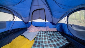 Een blauwe tent met een slaapgedeelte van binnen, inclusief een bed en een deken.