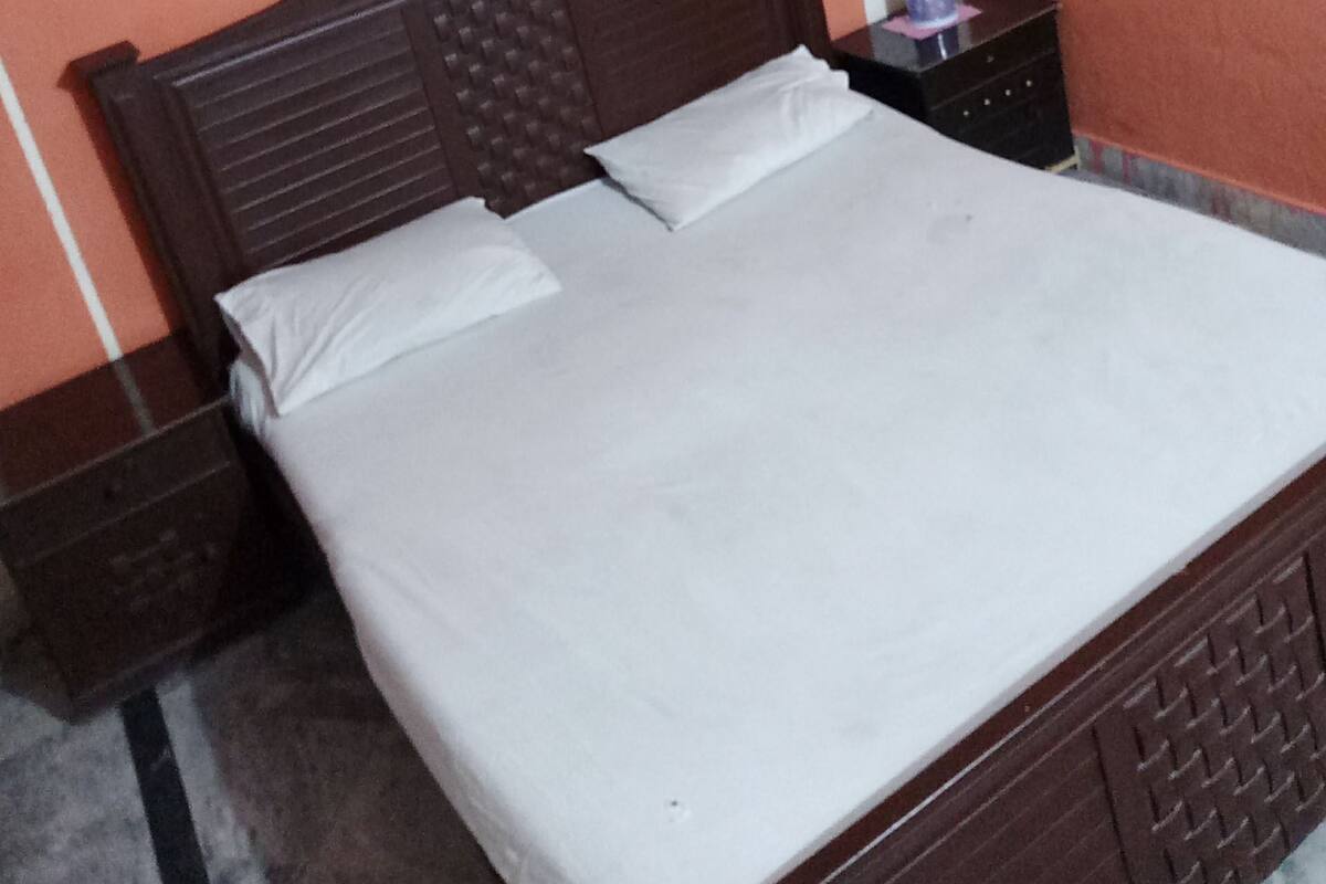 A neatly made bed with white linens in a room with a wooden headboard and a nightstand.