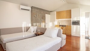 A modern bedroom with two beds, a small bedside table, and a kitchenette in the background. - Quinta do Casal de S. Miguel de Soutelo (Vila Verde)