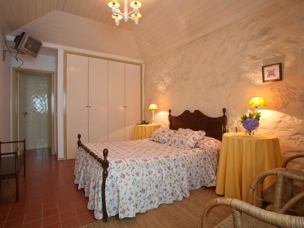 A bedroom with a wooden bed, two bedside tables with lamps, a chair, and a wardrobe.