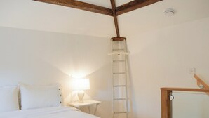 A bedroom with a bed, a nightstand with a lamp, a ladder, and a wooden ceiling beam. - 1 bedroom accommodation in Baschurch (Baschurch)