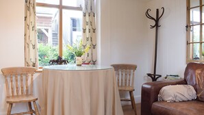 A cozy room with a round table, two wooden chairs, a brown leather sofa, and a floor lamp. - 1 bedroom accommodation in Baschurch (Baschurch)