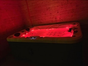 Una vasca idromassaggio con illuminazione rossa in una stanza in legno.