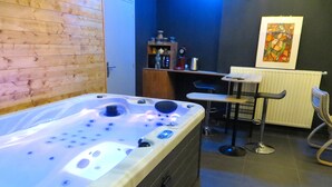 Une salle de bain moderne avec une grande baignoire, une petite table avec une chaise et un radiateur.