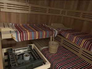 Una cabaña de madera con literas, un pequeño rincón de cocina y un calentador.