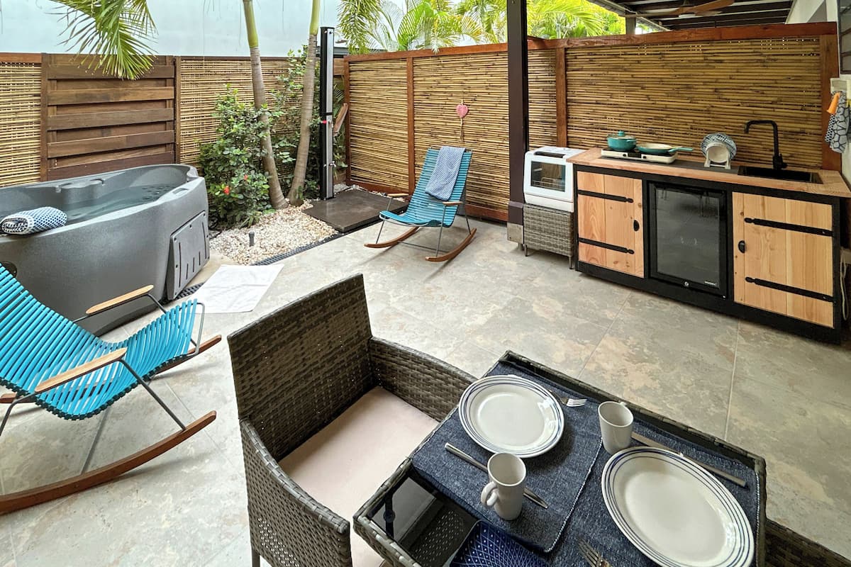 An outdoor patio with a grill, seating area, and a small kitchen setup.
