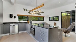 A modern kitchen with a central island, stainless steel appliances, and a decorative wall quote. - Deluxe Boutique Apartments Sonrisa Bonaire – Adults only (Kralendijk)