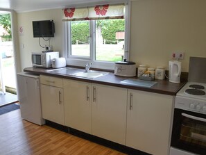 A compact kitchen with a sink, microwave, toaster, and a bread maker.