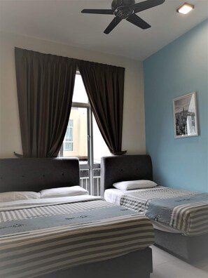 A hotel room with two beds, a ceiling fan, and a window with curtains.