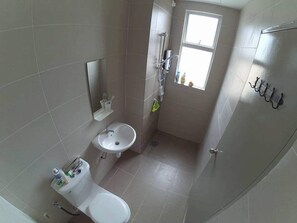 A small bathroom with a toilet, sink, and a window.