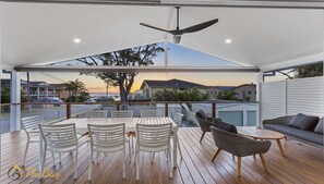 Un espace extérieur abrité, équipé d’une table et de chaises, d’un canapé et d’un ventilateur de plafond.