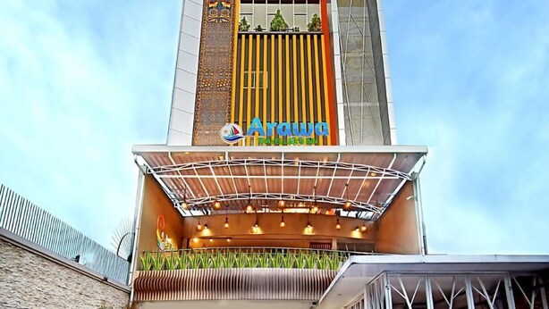 A modern building with a prominent sign for 'Arawa Travellers Inn'. - Arawa Traveller's Inn Makassar - Hostel (Makassar)