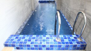A swimming pool with blue tiles and metal handrails. - Arawa Traveller's Inn Makassar - Hostel (Makassar)