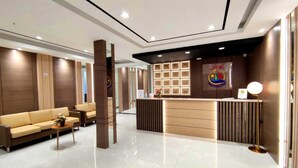 A modern hotel lobby with a reception desk, a sofa, and a coffee table. - Arawa Traveller's Inn Makassar - Hostel (Makassar)