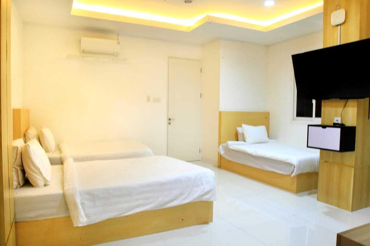 A hotel room with two beds, a flat-screen TV, and a ceiling-mounted air conditioner.