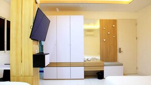 A bedroom with a bed, a TV mounted on the wall, a wardrobe, and a desk with a chair. - Arawa Traveller's Inn Makassar - Hostel (Makassar)