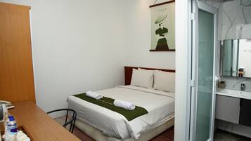 Une chambre d’hôtel comprenant un lit, une table de chevet et une salle de bain avec un lavabo et un miroir.