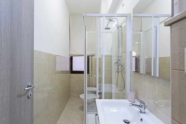 Une salle de bain moderne avec une douche à parois de verre, un lavabo blanc et des toilettes.