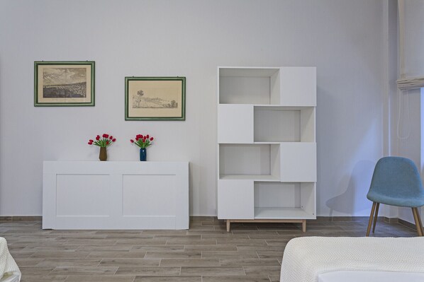 A room with a white console table, two framed pictures, a white shelving unit, and a blue chair. - XXV Aprile by Wonderful Italy - Salvia (Genova)