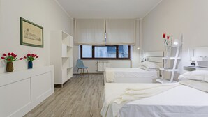 Un dormitorio moderno con dos camas, una ventana con cortinas, un radiador y una silla.