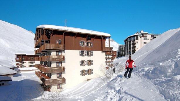 Ein mehrstöckiges Holzgebäude mit Balkonen, umgeben von schneebedeckten Hängen.