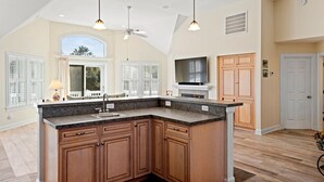A spacious kitchen with a large island, wooden cabinets, and pendant lighting. - Brown Dog by the Sea: Soundside, Private Pool, Spa (Corolla)