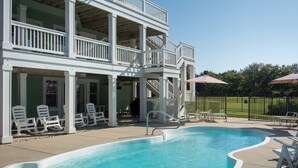 A two-story building with a swimming pool, outdoor seating, and a fenced yard. - Brown Dog by the Sea: Soundside, Private Pool, Spa (Corolla)