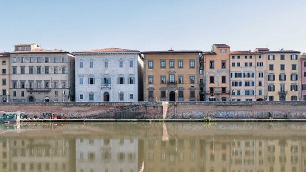 Una hilera de edificios históricos a lo largo de un río con reflejo claro.