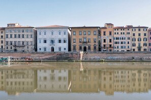 A row of historic buildings along a river with a clear reflection.
