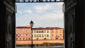 Vista a través de un puerta decorada, con un farol en primer plano, que da a una hilera de edificios con tejados de tejas rojas y contraventanas verdes.