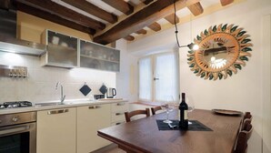 Una cocina moderna con una mesa de comedor de madera, electrodomésticos de acero inoxidable y un espejo decorativo.