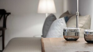 Una cama bien hecha con almohadas y una mesita de noche con dos vasos.