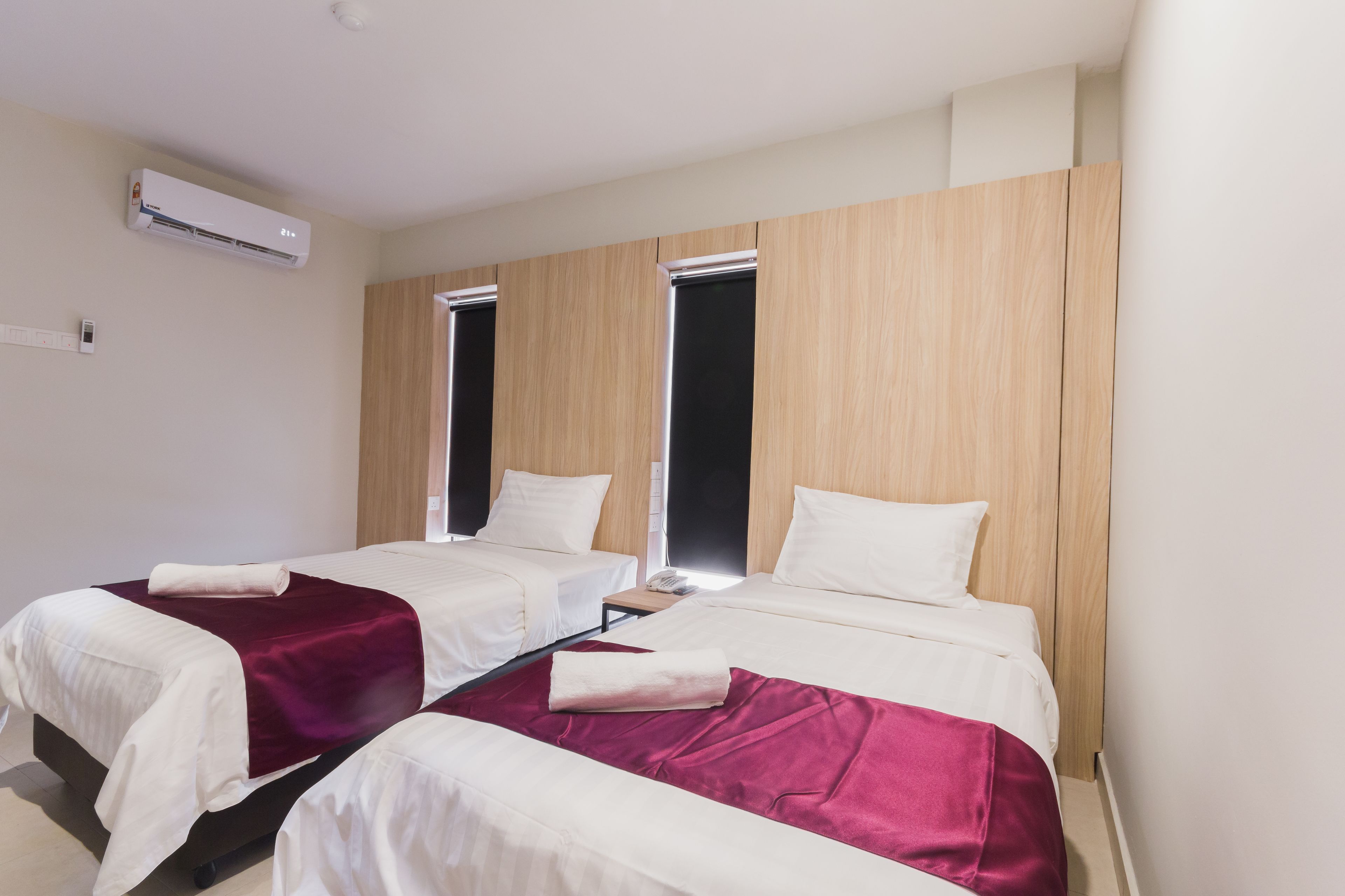 Une chambre d’hôtel avec deux lits, une armoire en bois, un appareil de climatisation et une fenêtre.