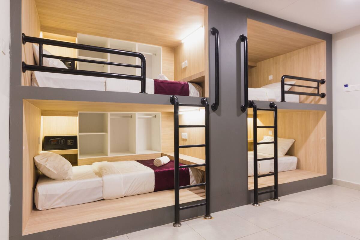A multi-level bunk bed room with a desk and shelving unit.