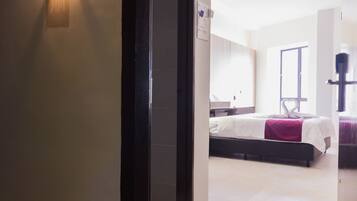 Una habitación de hotel con una cama, un escritorio y una ventana.