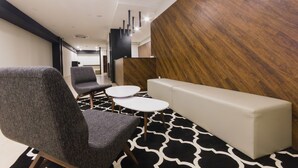 Um interior moderno com um sofá, duas mesas redondas e um banco comprido.