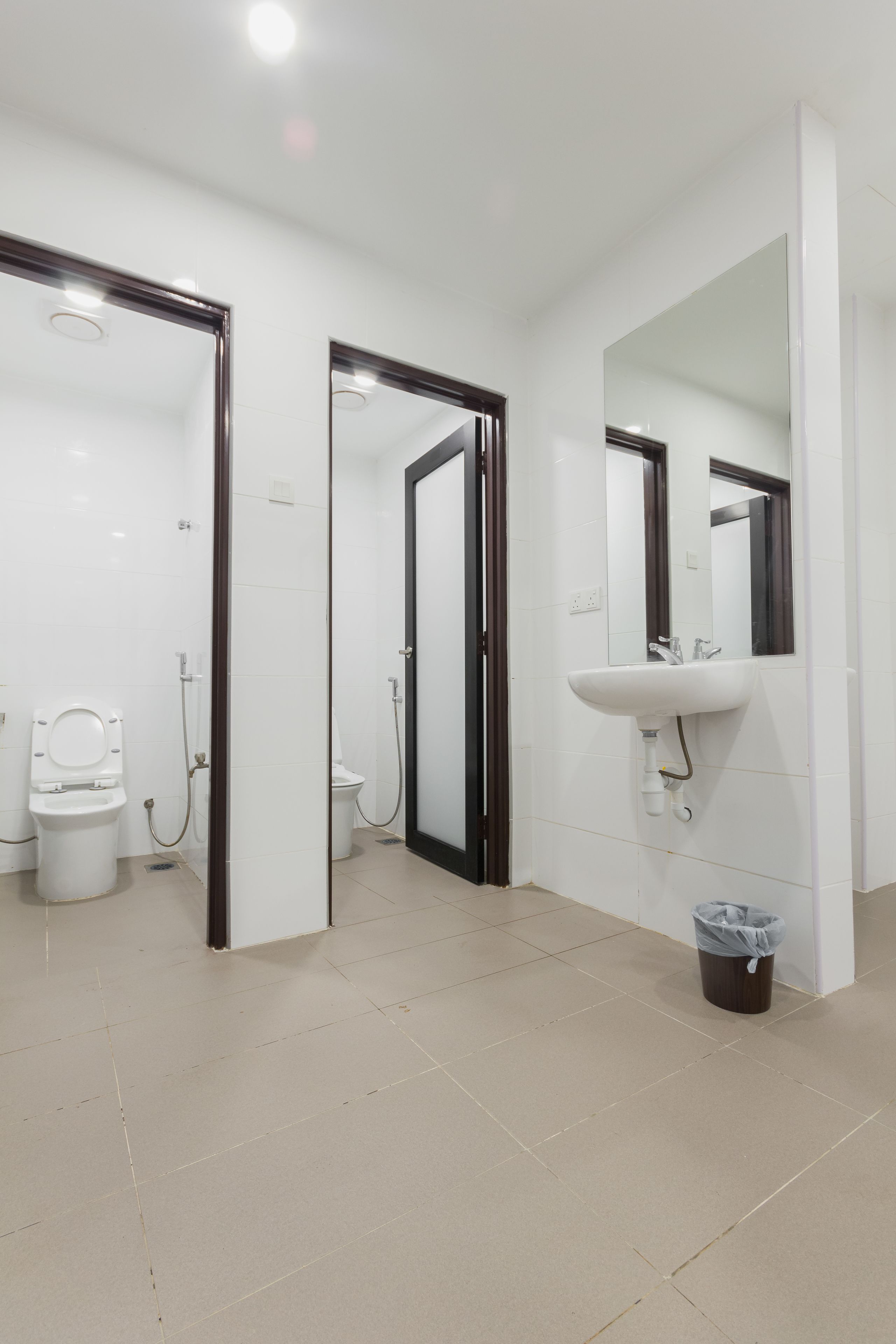 A modern bathroom with a white sink, a mirror, and two toilets.