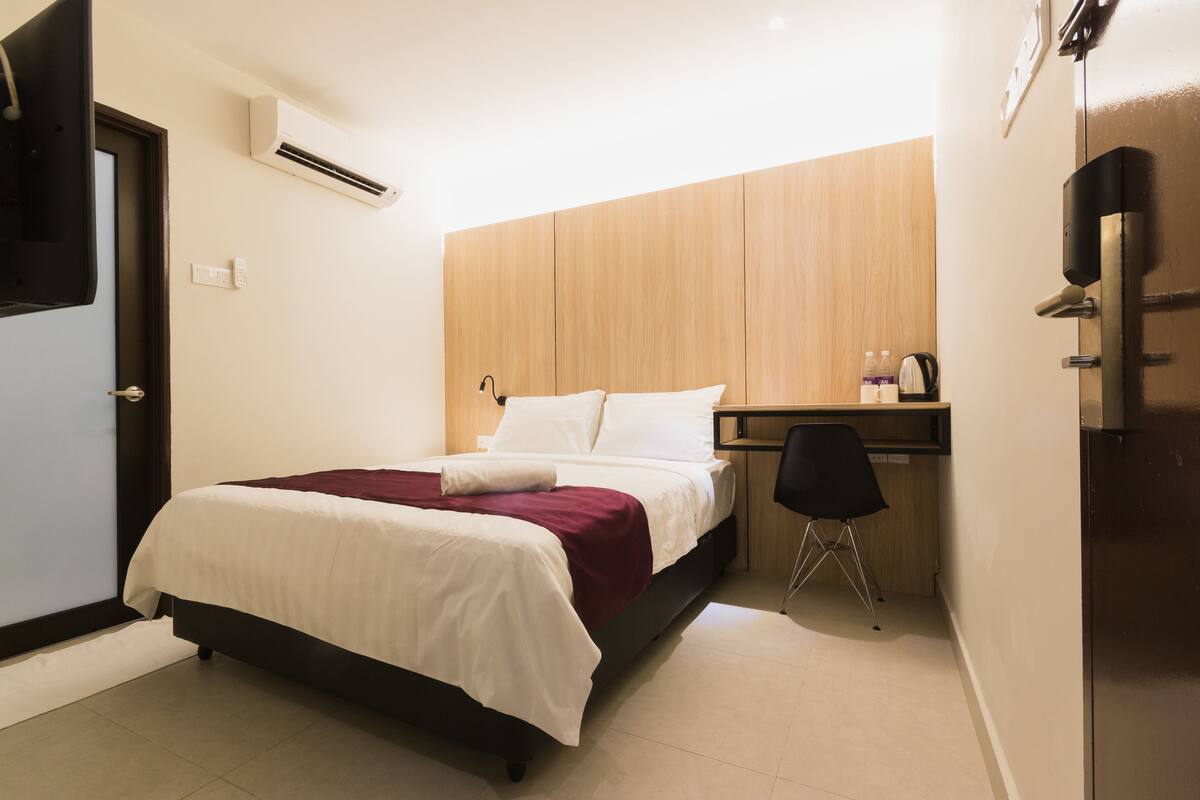 A bedroom with a bed, a desk, and a chair.