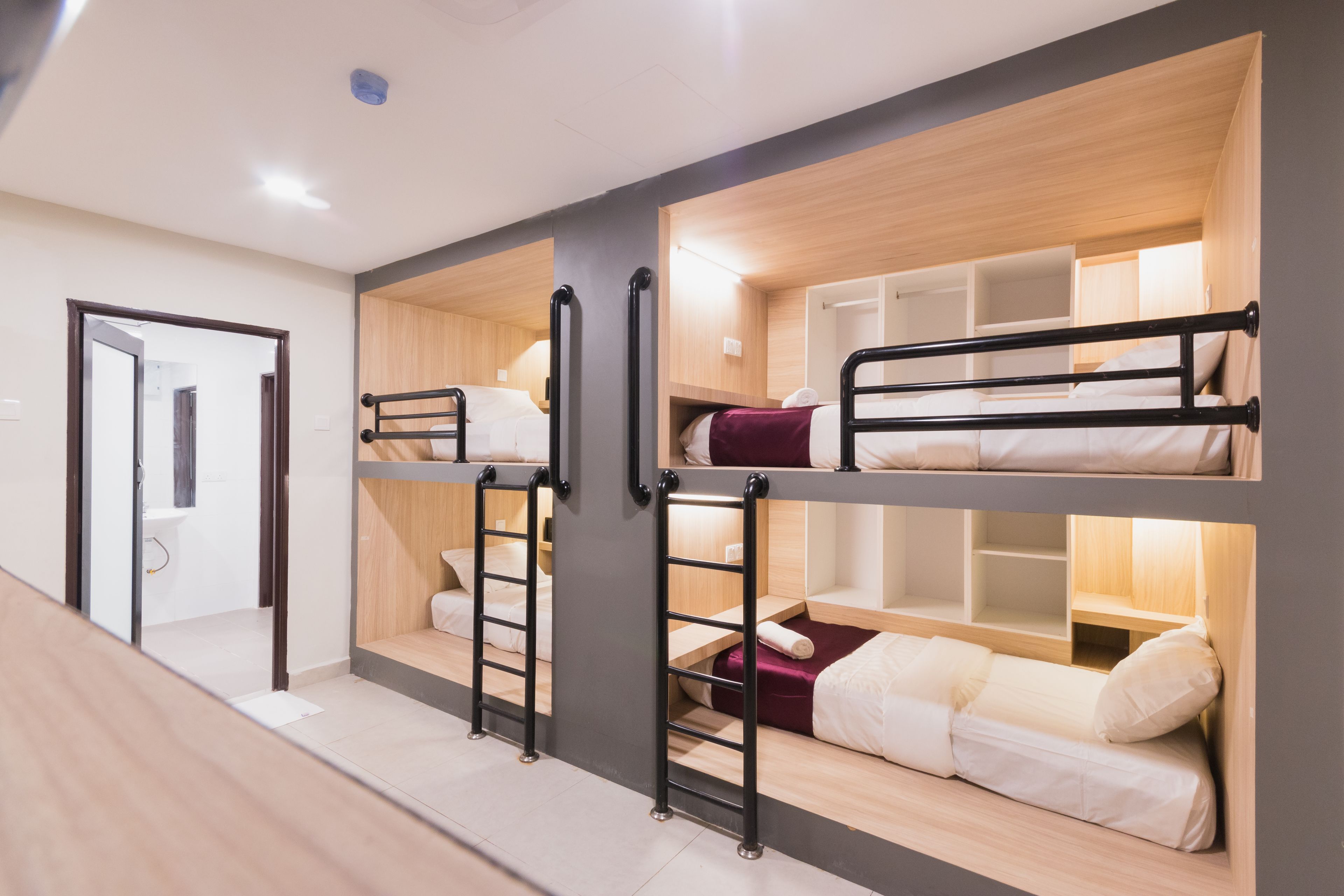 A bunk bed room with a wooden floor, a door, and a small shelf.