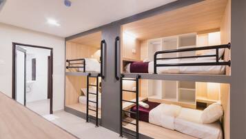 A bunk bed room with a wooden floor, a door, and a small shelf.