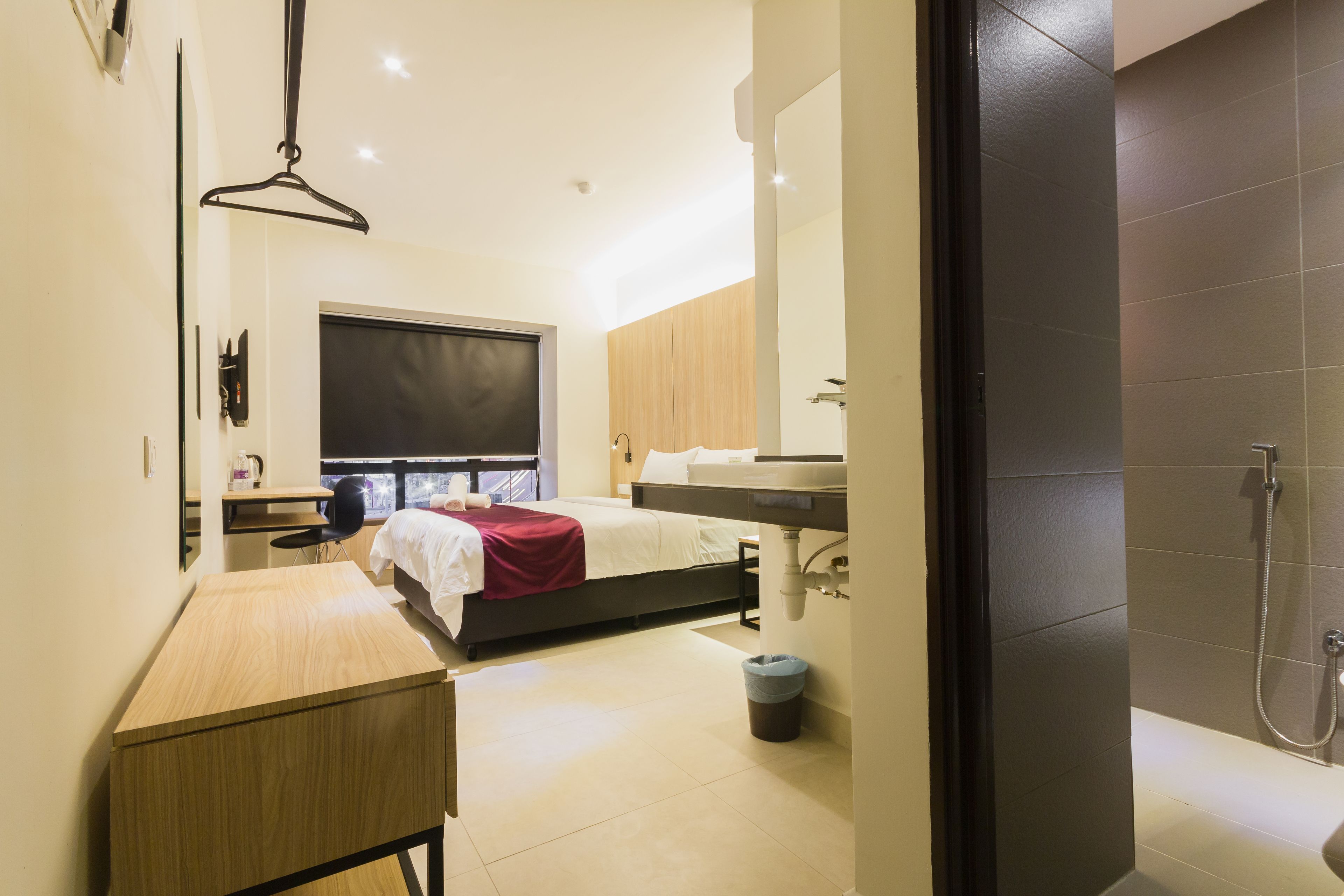Une chambre d’hôtel moderne équipée d’un lit, d’un bureau et d’un espace douche.