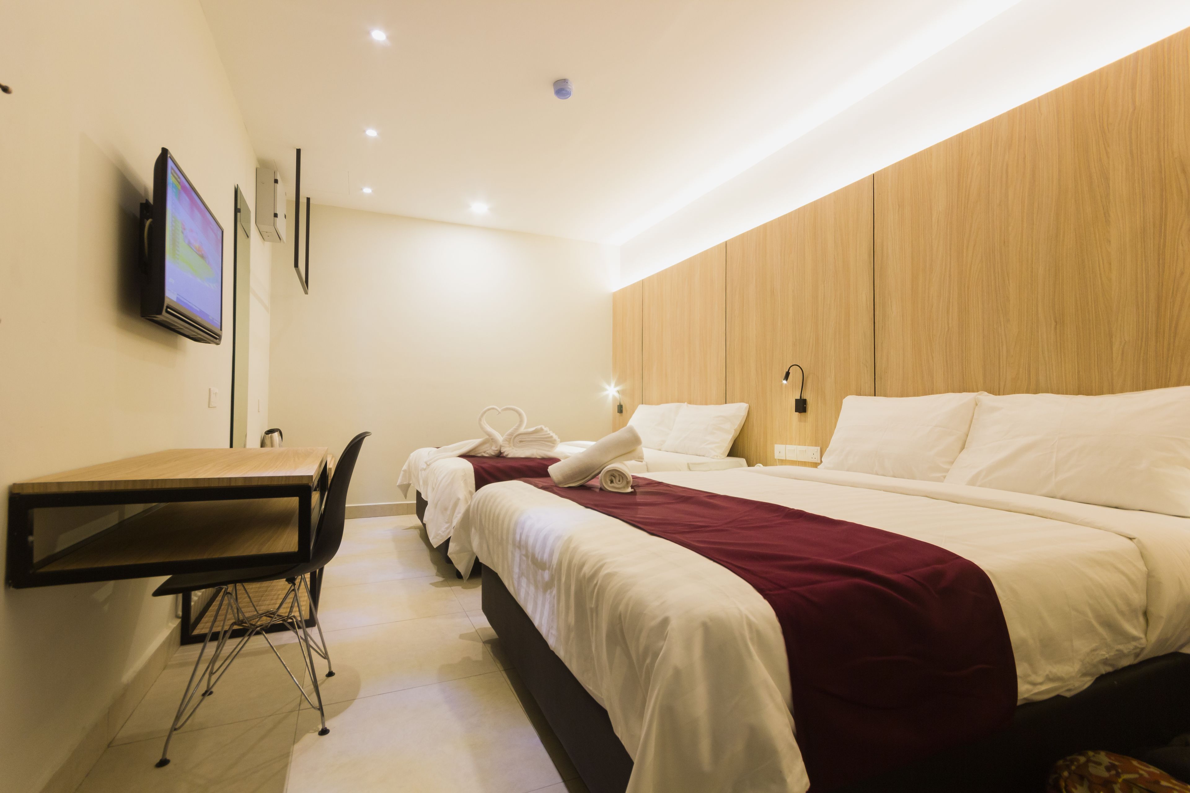 Une chambre d’hôtel avec un lit, un bureau et une chaise. Un téléviseur est fixé au mur.