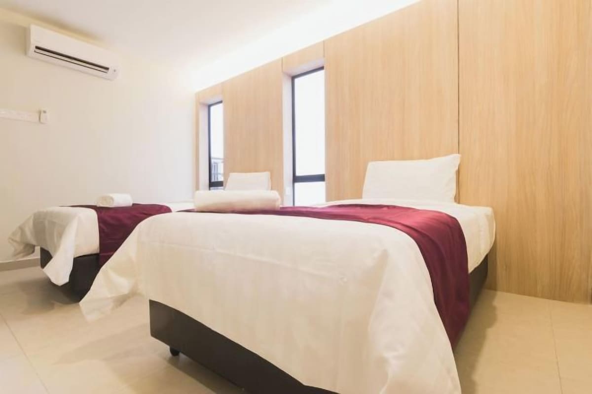 Une chambre d’hôtel avec deux lits, une grande fenêtre et un panneau mural en bois.