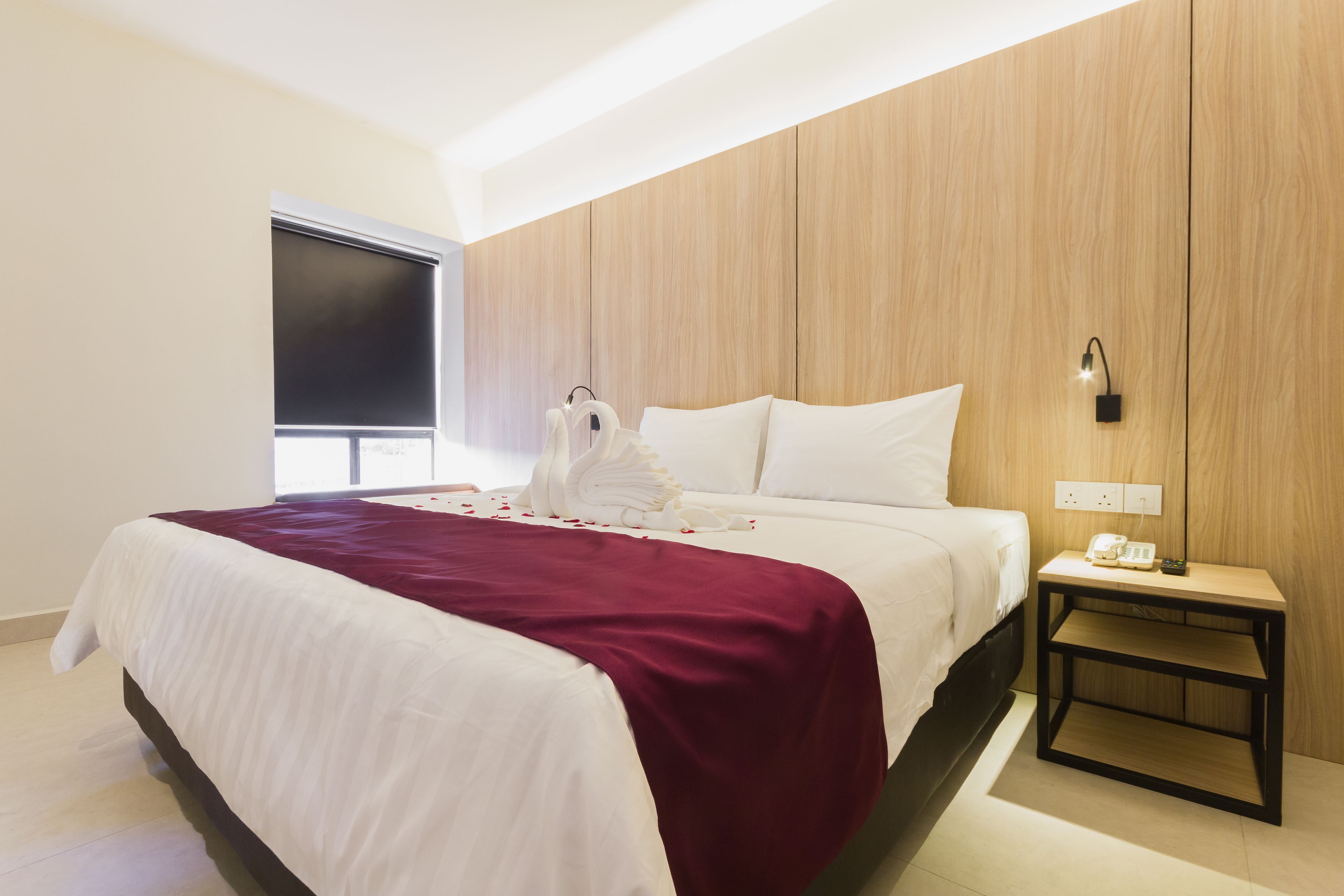 Una habitación de hotel con una cama, una mesita de noche, un teléfono en la pared y una ventana.