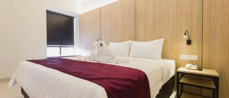 Una habitación de hotel con una cama, una mesita de noche, un teléfono en la pared y una ventana.