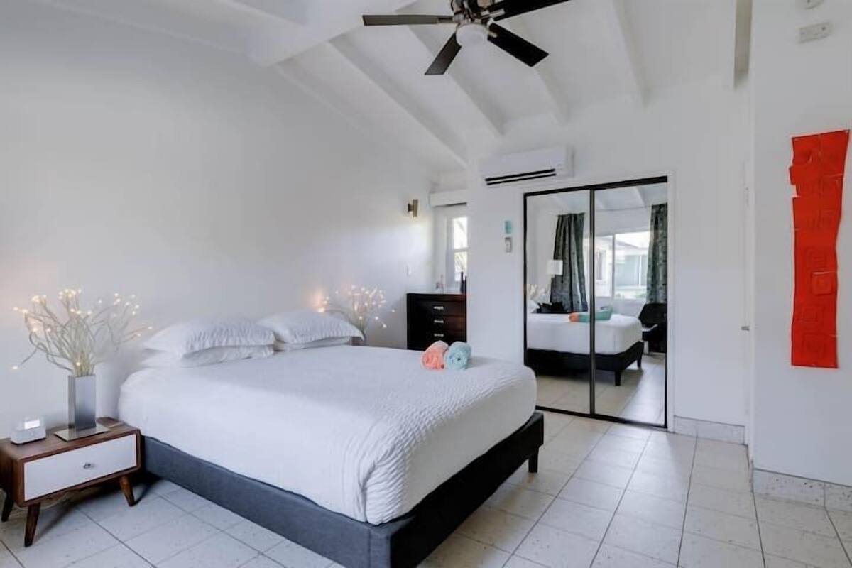 A bedroom with a bed, bedside table, nightstand, and a ceiling fan.
