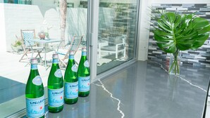 A glass table with four bottles of S. Pellegrino water and a large green plant. - BelleVue Oasis-Palm Springs - Adults Only (Palm Springs)