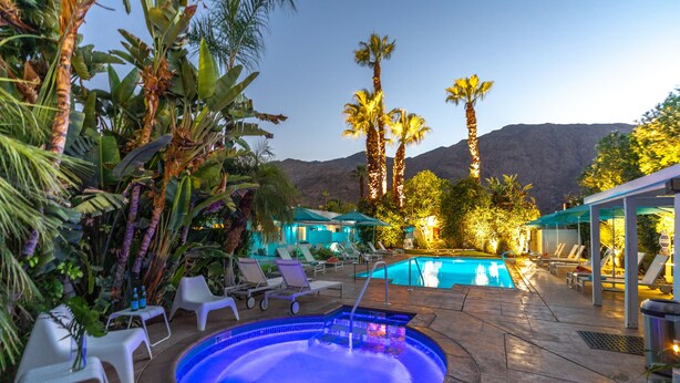 A pool area with lounge chairs and a hot tub, surrounded by tropical plants and palm trees. - BelleVue Oasis-Palm Springs - Adults Only (Palm Springs)
