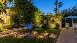 A well-lit garden with a pool, stone pathways, and outdoor seating. - BelleVue Oasis-Palm Springs - Adults Only (Palm Springs)