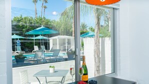 A room with a view of a pool, a table with a bottle of champagne, and two glasses. - BelleVue Oasis-Palm Springs - Adults Only (Palm Springs)
